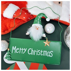 Close-up of green metal Merry Christmas sign with plush Santa doll and star pendant