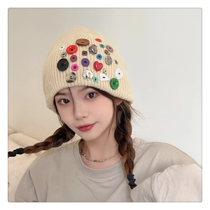 Front view of beige knit beanie featuring colorful decorative buttons on a model