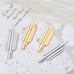 Minimalist long metal tassel drop earrings in gold and silver finish on a stone platform