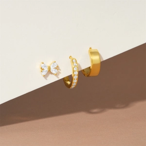 Detailed view of a 3-piece gold S925 silver earring set with zircon bow and hoop designs