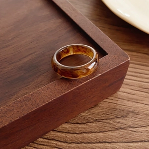 Close-up of vintage amber resin ring with internal silver metal plating on wood