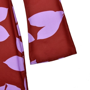 Détail du tissu rouge foncé avec imprimé feuilles violettes et coutures du poignet