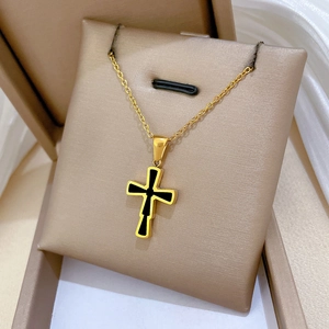 Macro shot of double-sided cross pendant on gold chain necklace in a cream jewelry box