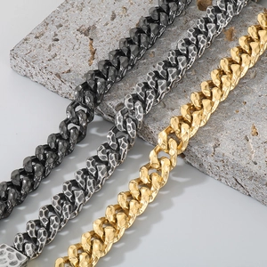 Detail of hammered texture Cuban chains in gold and silver finish on stone background