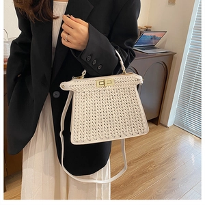 Close-up of white woven leather handbag with gold turn-lock closure on model
