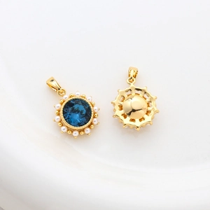 Detail eines 14k vergoldeten Anhängers mit blauem Edelstein und Perlen auf weißem Grund