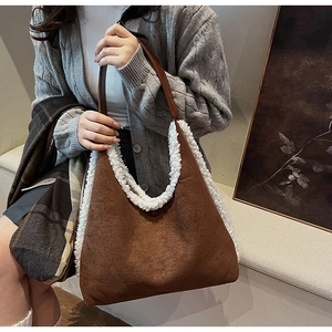 Detail of brown faux suede tote bag with white faux shearling trim and leather strap