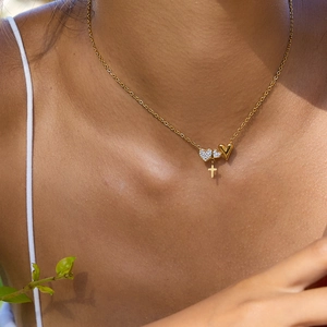 Minimalist gold heart and cross pendant necklace with zircon stones on female model