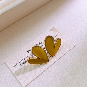 Detailed macro shot of mustard yellow heart earrings with polished enamel and gold metal base