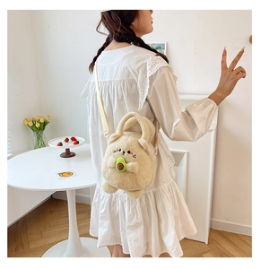 Detail shot of a beige plush animal crossbody bag with an avocado accent on a model