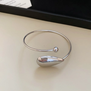 Detail of silver drop-shaped and round bead open cuff bracelet with metallic finish