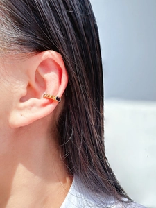 Detail of gold chain ear cuff with blue rectangular zircon on model's ear
