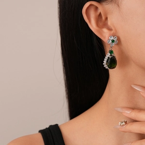 Detailansicht von smaragdgrünen Wassertropfen-Ohrringen mit Zirkonia-Blumen am Model