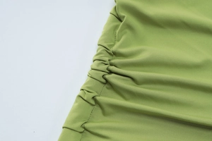 Detailed view of lime green knit fabric with decorative side ruching and gathering detail