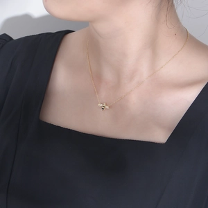 Detail shot of a gold bee pendant necklace with sparkling wings worn by a model