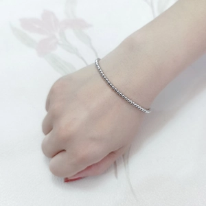 Close-up of a silver beaded elastic stainless steel bracelet on a person's wrist