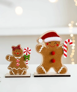 Close-up of felt gingerbread man and woman wooden ornaments with festive bokeh lighting