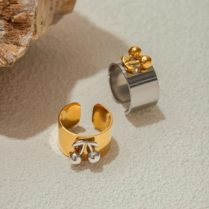 Macro shot of gold and silver cherry wide band rings on a natural stone and sand surface