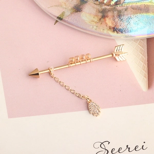 Detail of golden arrow industrial barbell with amber beads and crystal Hamsa Hand charm