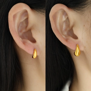 Minimalist golden teardrop earrings with a polished finish shown on a female model