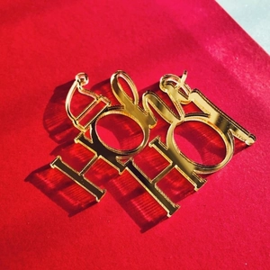 Detailed view of golden acrylic Ho Ho Ho Christmas cake topper on a red textured surface