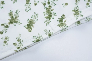 Detalle macro de la tela floral blanca con estampado verde y doble costura de precisión