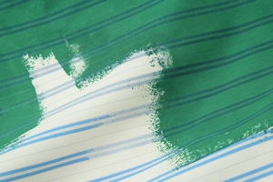 Detailed close-up of green striped fabric texture with artistic white and blue patterns