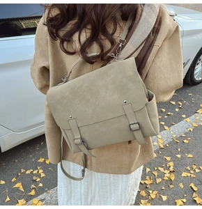 Khaki matte backpack with flap design shown on model in an outdoor street setting