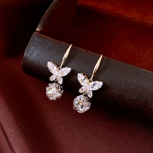 Boucles d'oreilles papillon dorées élégantes avec zircons sur une texture cuir de luxe