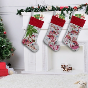 Three Christmas stockings with flamingos and fairy lights hanging on a festive fireplace mantel
