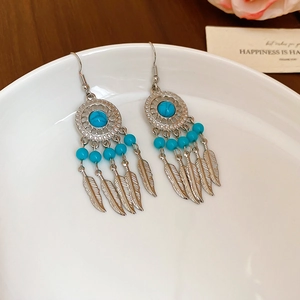 Detail of silver bohemian earrings with turquoise beads and delicate feather pendants