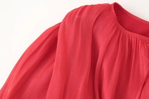 Dettaglio della manica a sbuffo rossa con trama a pieghe e tessuto chiffon di lusso