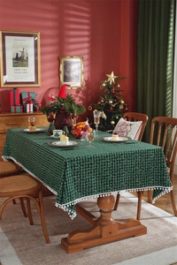 Detailed view of green and black plaid Christmas tablecloth with white pom pom fringe