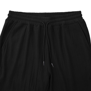 Detail of elastic waistband and drawstring on black vertical textured knit pants