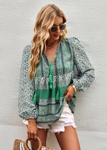 Detail of bohemian printed blouse with tassels and V-neckline in green and blue