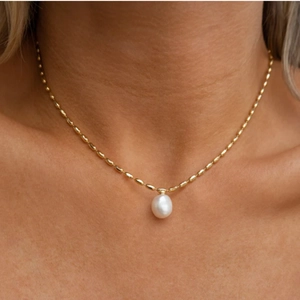 Collier élégant en chaîne dorée avec pendentif perle goutte porté par un mannequin