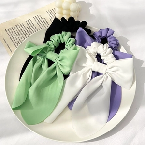 Vierer-Set Satin-Haargummis mit Schleife in Schwarz, Grün, Lila und Weiß auf Teller