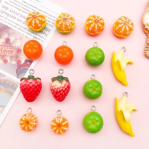 DIY colorful acrylic fruit charms featuring orange, strawberry, and lemon on pink surface