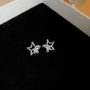 Close-up of star-shaped silver earrings with sparkling zircon inlay on black velvet