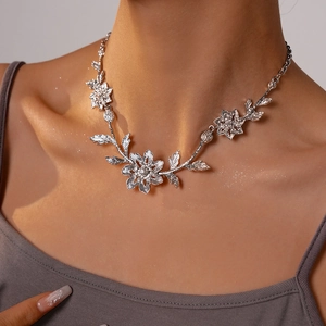 Close-up of floral silver necklace with textured metal leaves on a model's neck