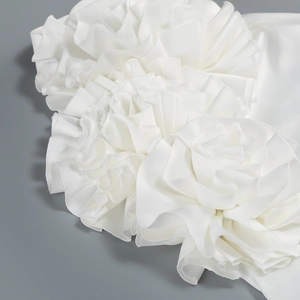 Détails des fleurs en tissu 3D et de la texture plissée sur la robe blanche élégante