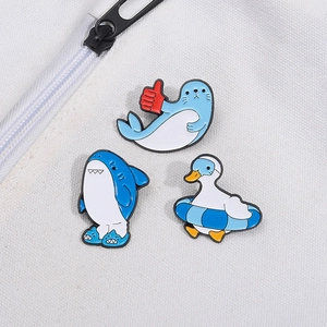 Cute enamel pins featuring cartoon seal, shark, and duck with swim ring on canvas bag