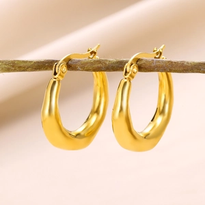 Macro shot of 18K gold geometric hollow earrings hanging on a natural wooden branch