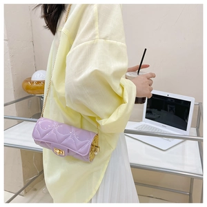 Detail of purple patent leather cylinder bag with gold chain worn by a model