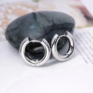 Detailed macro view of polished silver thick hoop earrings with a secure clasp closure