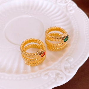Macro detail of gold-plated twisted rings with green and orange teardrop zircon stones