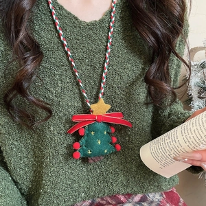 Close-up of green plush Christmas tree pendant with red bow and woven rope necklace
