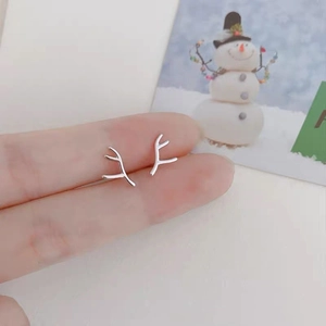 Close-up of minimalist silver reindeer antler earrings held on a finger for size