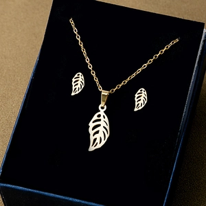 Close-up of golden leaf necklace and earrings set in a premium velvet jewelry box