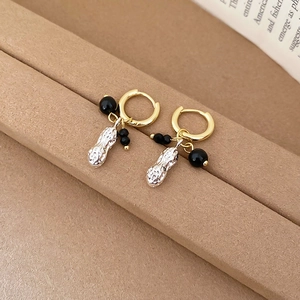 Macro view of vintage gold hoop earrings with peanut pendant and black crystal beads